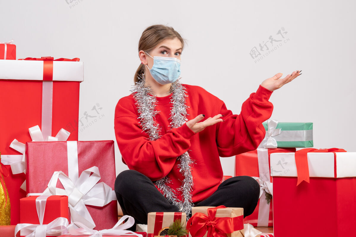 坐着正面图：年轻女性戴着无菌面具坐着 手里拿着圣诞礼物圣诞节礼物绝育