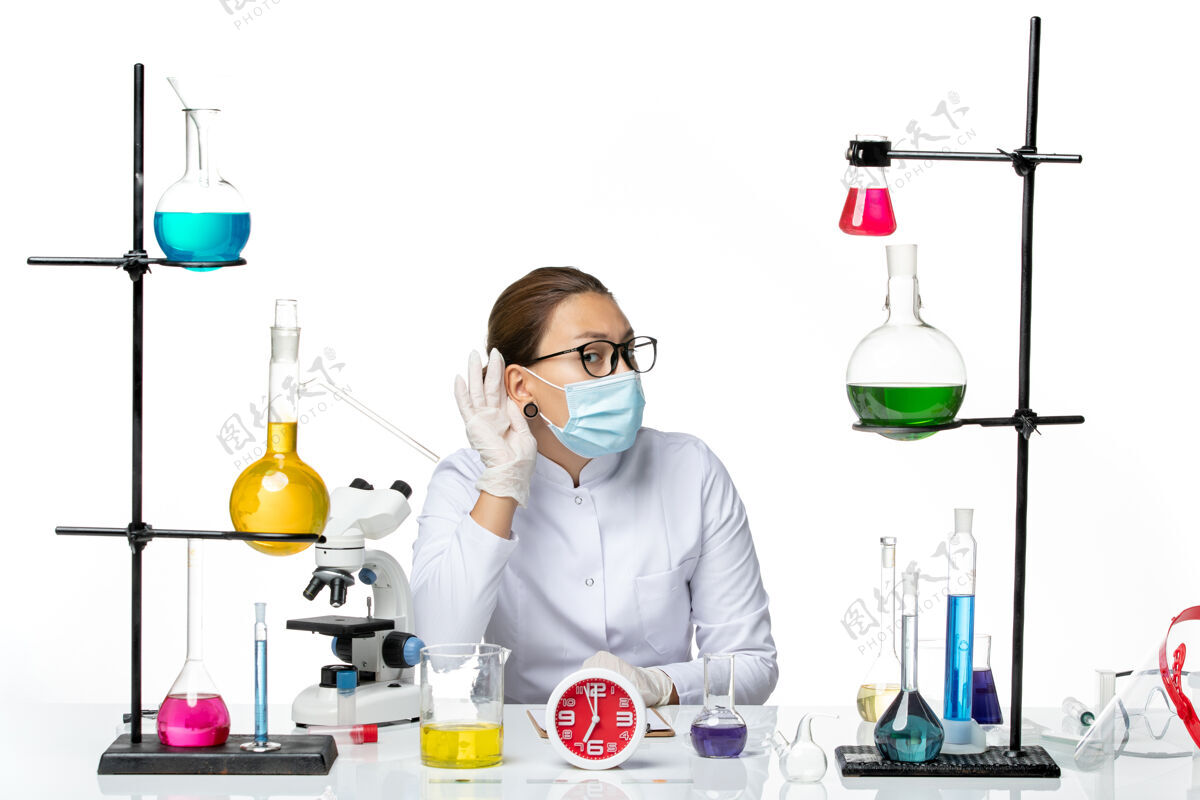 面具前视图穿着医疗服的女化学家带着面罩坐在白色背景上试图听到化学家实验室病毒的喷溅声化学家病毒实验室