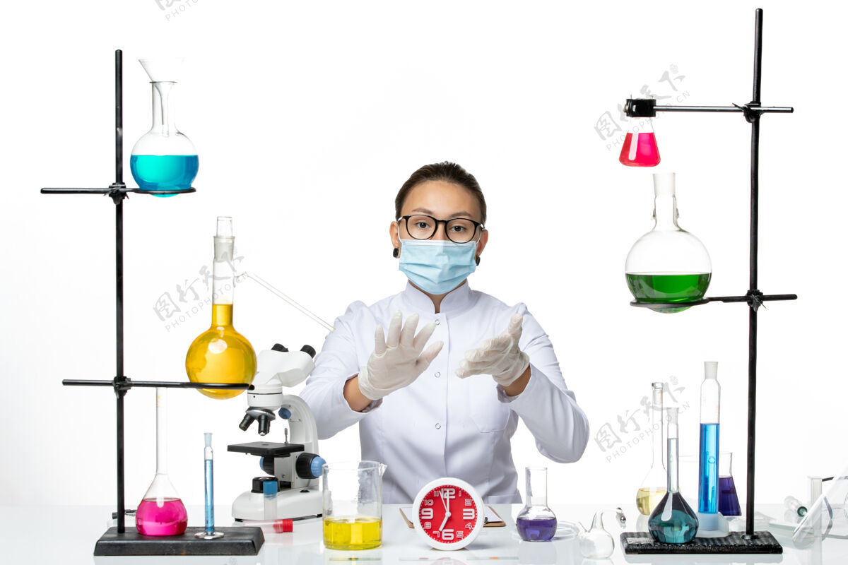 科学前视图穿着白色医疗服戴着面具的女化学家正坐在白色背景上化学家病毒冠状病毒-飞溅实验室坐化学视图