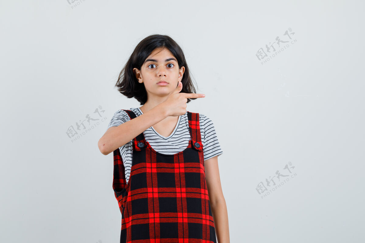 学校穿着t恤 连身衣的少女指着左边 看上去很小心模特时髦自信