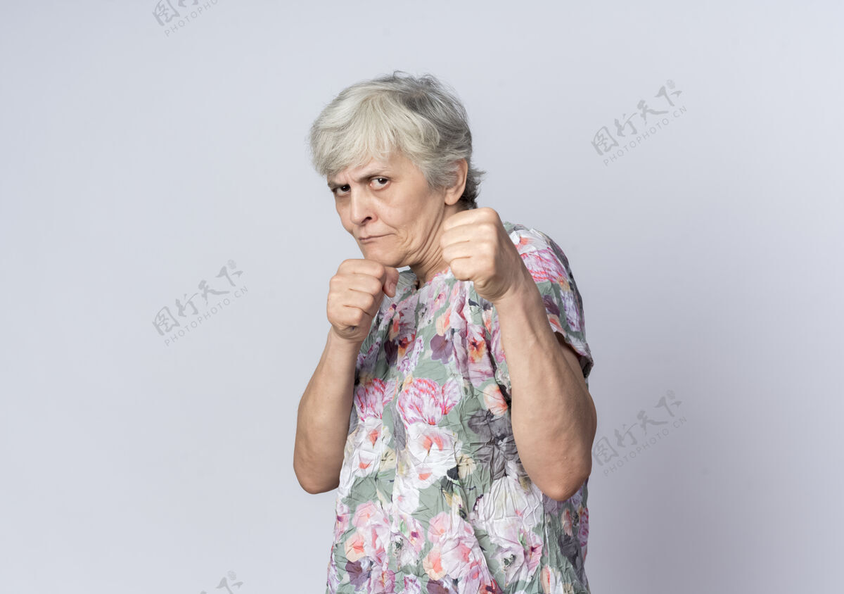 保持自信的老妇人用拳头准备在白色的墙上击打准备女人拳头