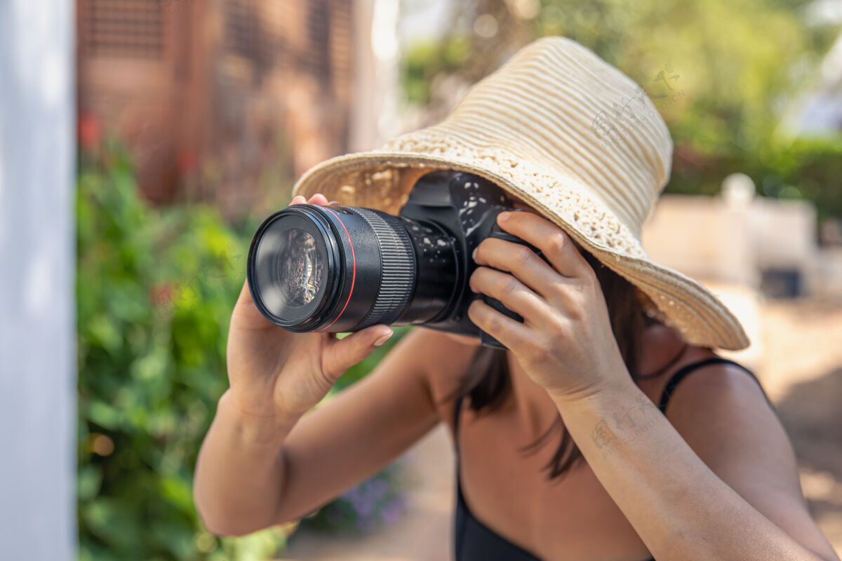 乡村炎炎夏日 一位戴着帽子的年轻女子用专业单反相机拍照女人休息爱好