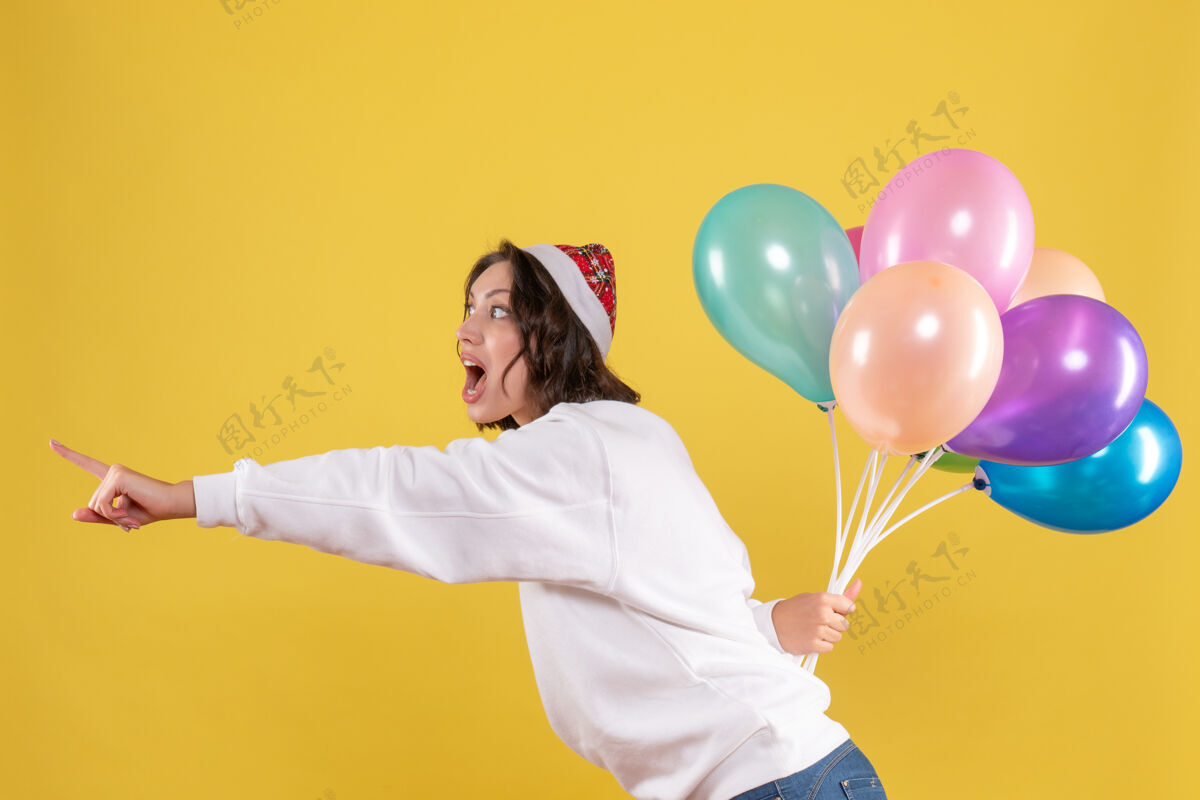 情感正面图年轻女子藏着五颜六色的气球新年圣诞彩绘节日女子感慨多彩女人前面