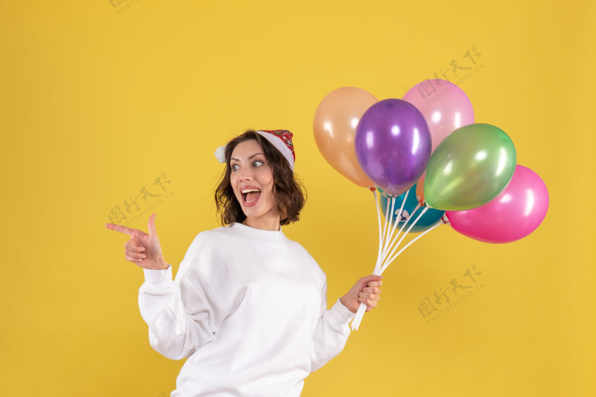 多彩正面图美丽的女性手持五颜六色的气球站在黄色女人情感飞机