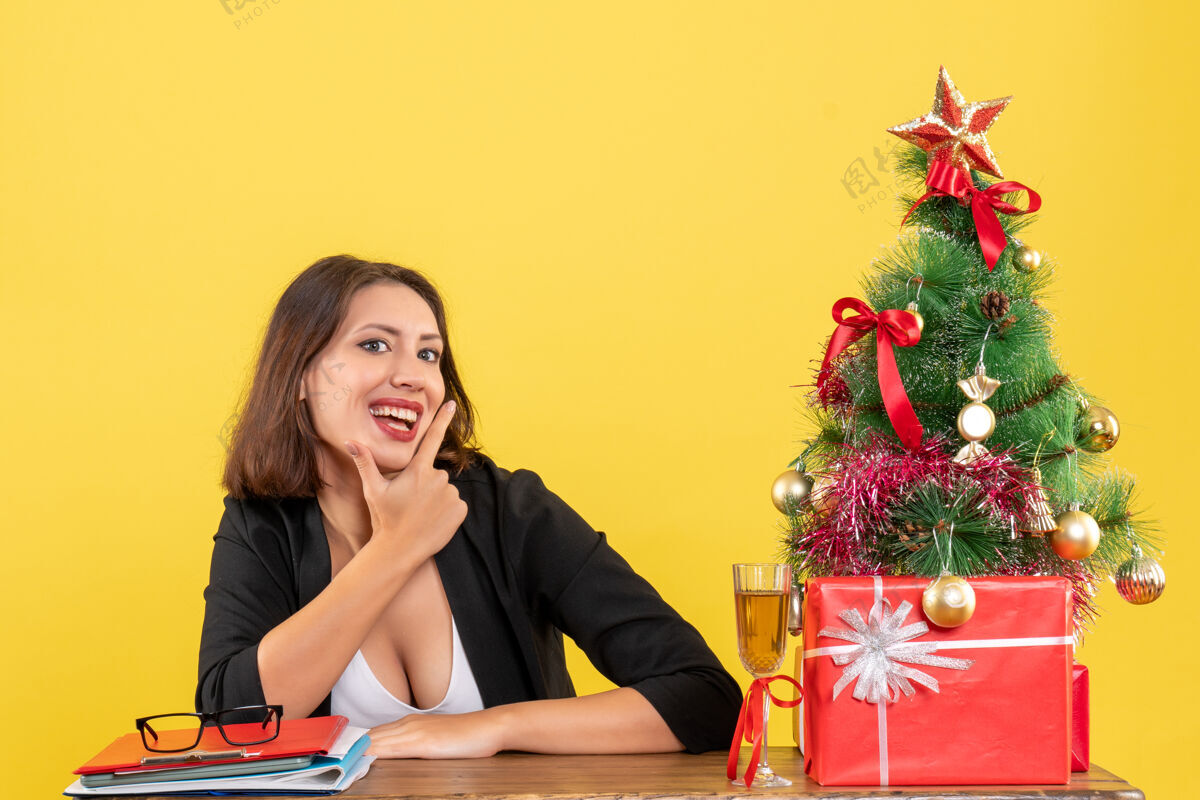 黄色Xsmas心情与年轻快乐的商务女士坐在办公室孤立的黄色背景笔记本电脑快乐人