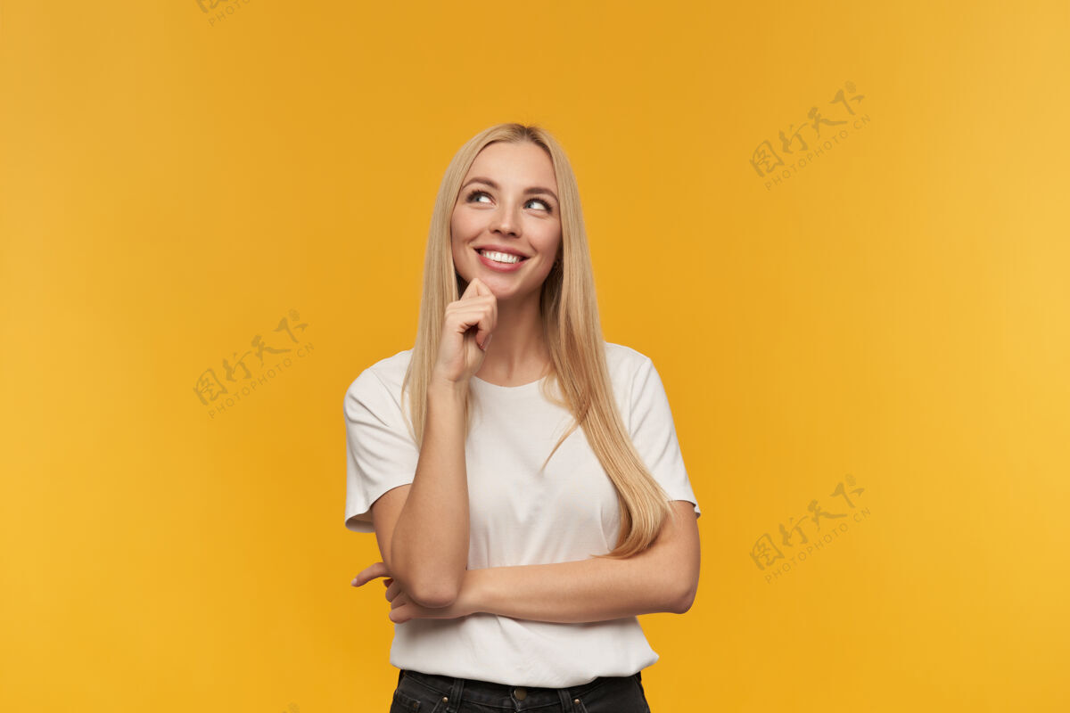 T恤有吸引力的 金发的成年女孩的肖像穿着白色t恤和黑色牛仔裤人和情感的概念在复制空间观看 橙色背景下孤立脸成人女性