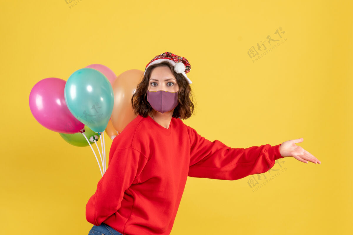 消毒正面图年轻女性隐藏在无菌面具气球圣诞假期色彩情感女人新年气球前面年