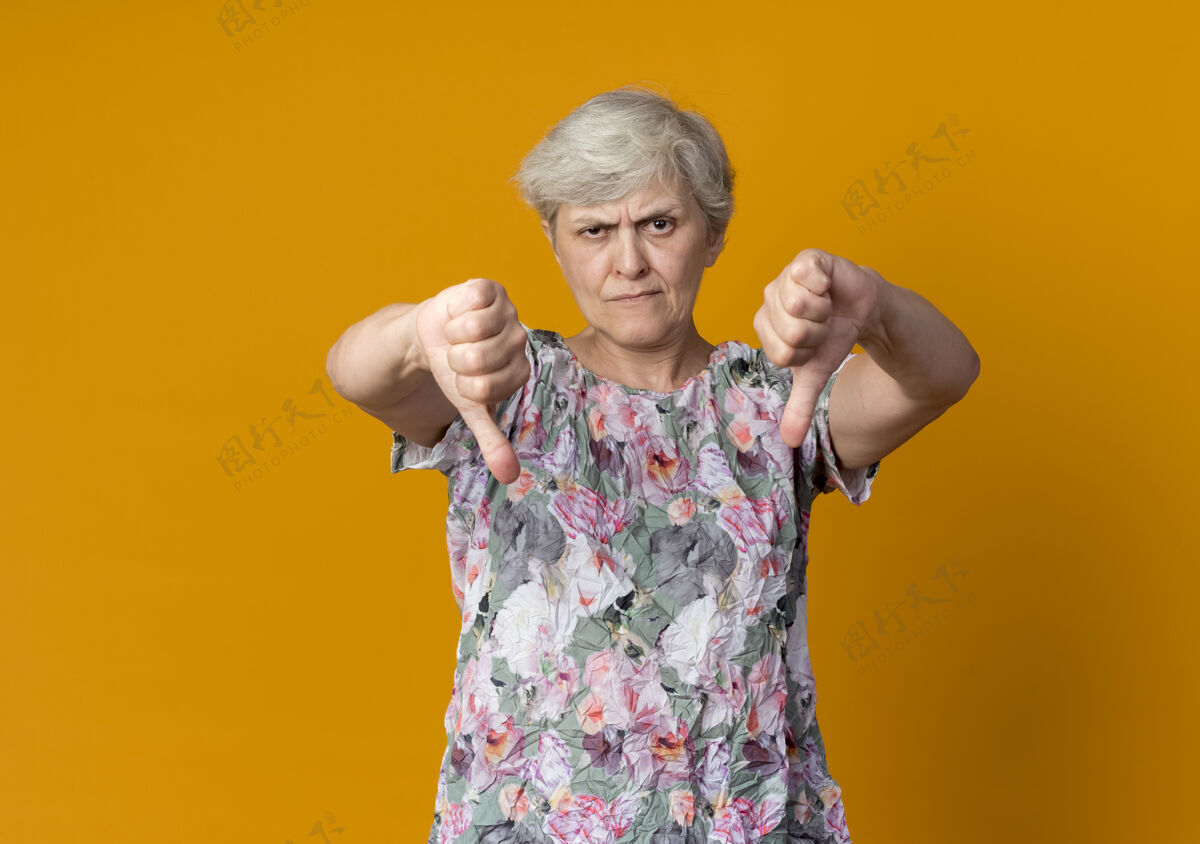 四个自信的老妇人竖起大拇指 两只手分别放在橙色的墙上女人自信橙色