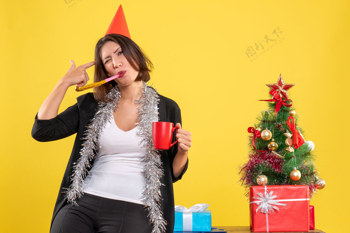 性感圣诞心情与搞笑美丽的女士手持红色杯子在黄色的办公室快乐成人性感