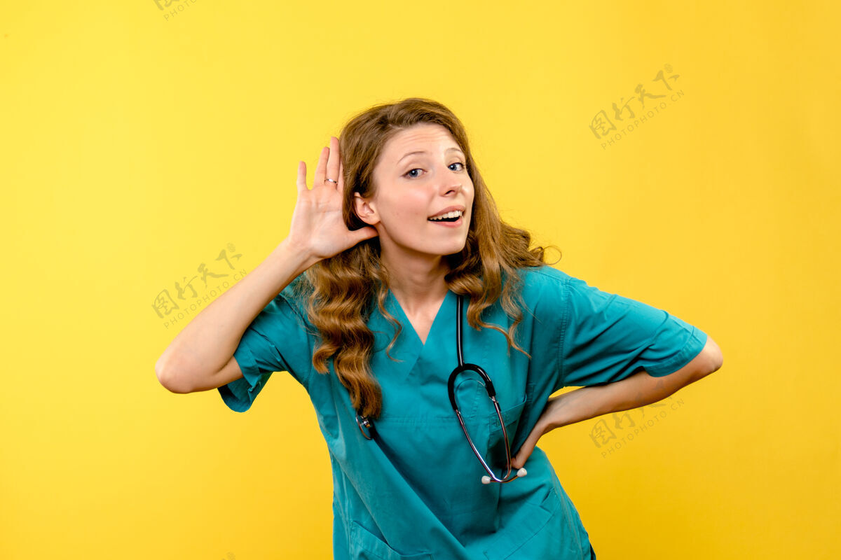 制服女医生在黄墙上听的正视图黄色医生护士