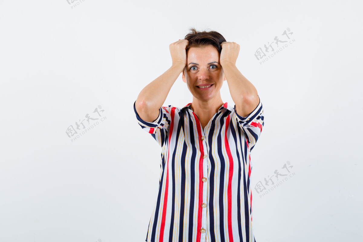 成人成熟的女人手举在头上 穿着条纹衬衫微笑着 看起来很活泼正面图年龄衬衫健康