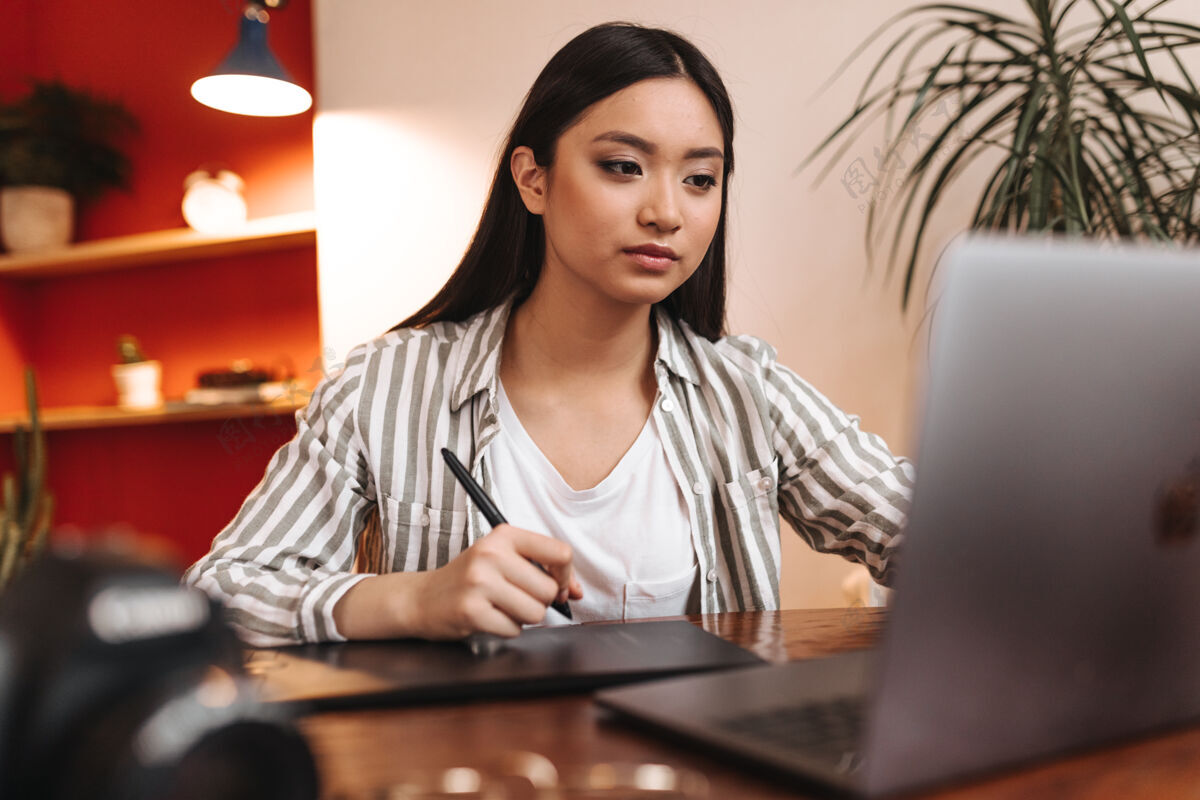 亚洲严肃的棕色眼睛的亚洲女人在办公室工作 拿着笔记本电脑和钢笔眼镜人咖啡馆