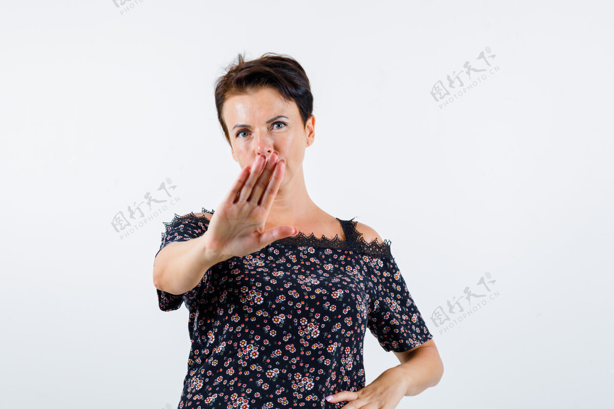 成人成熟的女人展示停车标志 手放在腰上 穿着花衬衫 黑色裙子 看起来很自信正面图信心持有衬衫