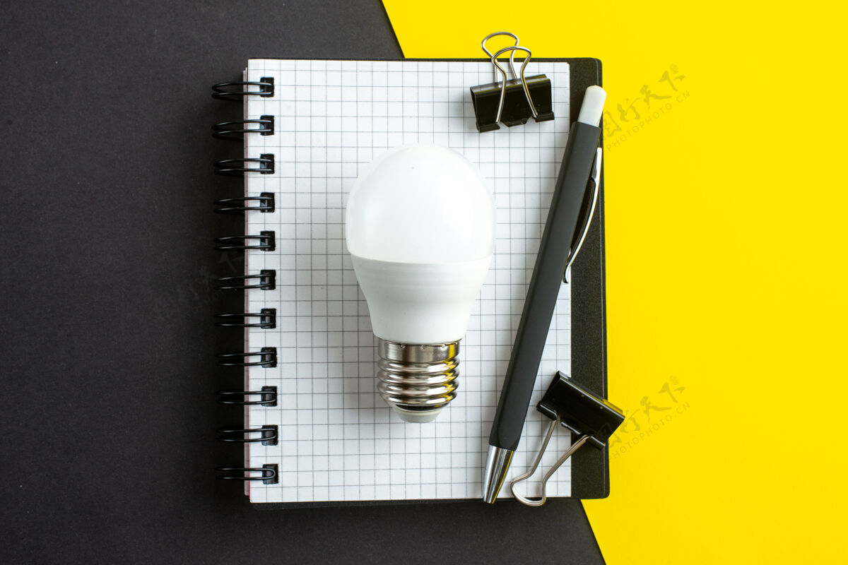 笔顶视图的灯泡螺旋笔记本上的书和笔黑黄色的背景与自由空间金属设备数据