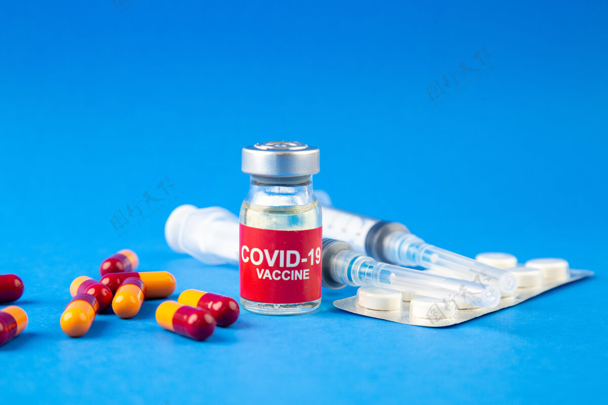 药房蓝色波浪背景上的柯维疫苗安瓿和胶囊包装药丸注射器前视图正面胶囊药品