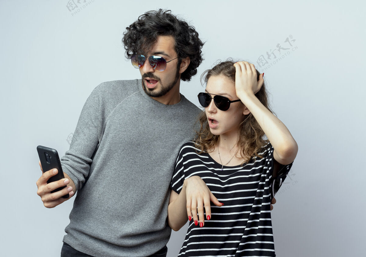 站起来一对年轻夫妇惊讶地看着站在白色背景上的智能手机屏幕情侣手机惊喜