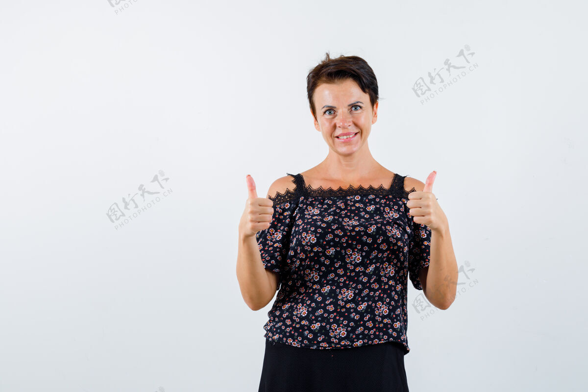 前面成熟的女人在花衬衫和黑色裙子上竖起大拇指 看起来很开朗 正面视图年龄自信成熟