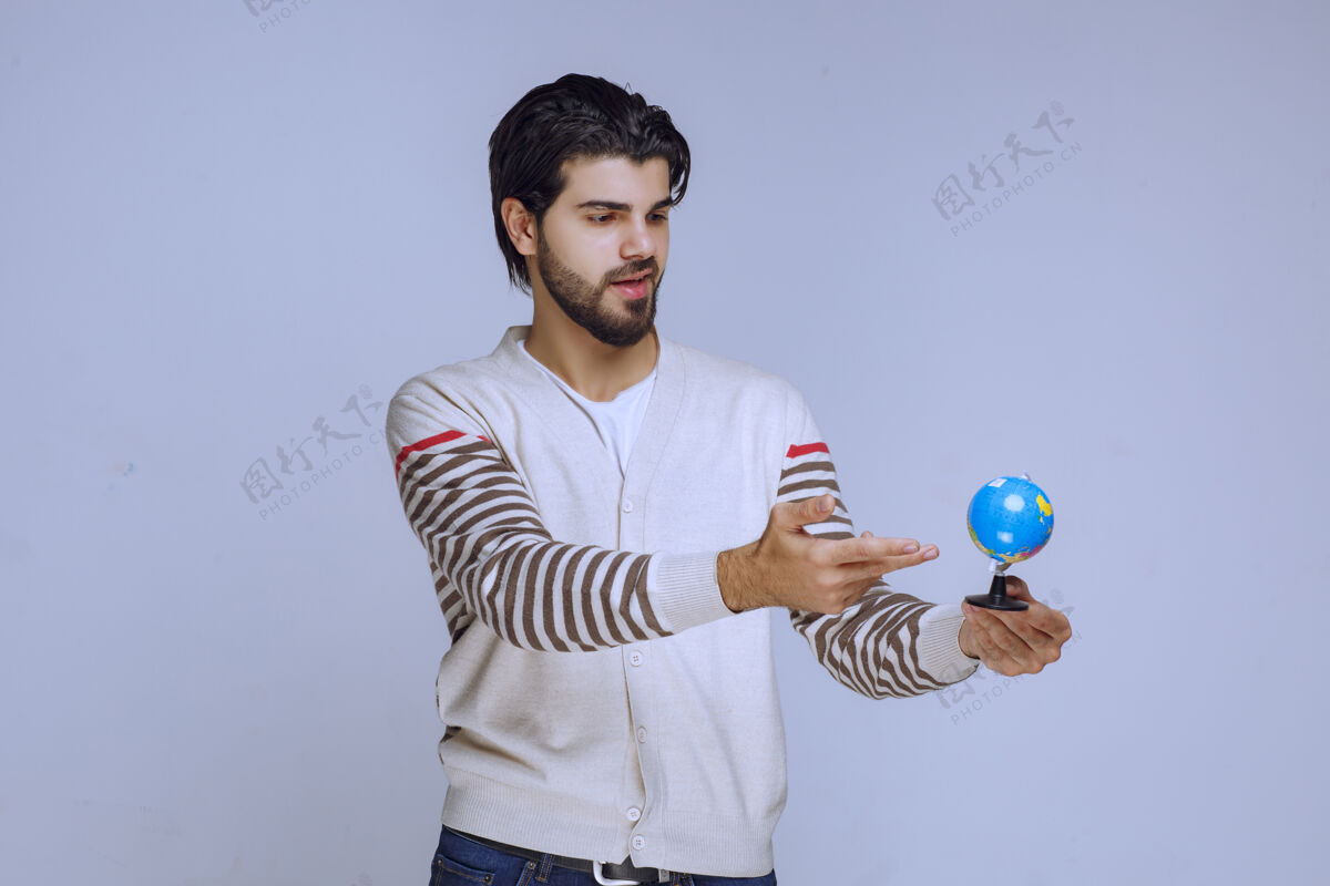 娱乐男人拿着一个迷你地球仪 摇晃着它 试图猜一个位置服装人类学生