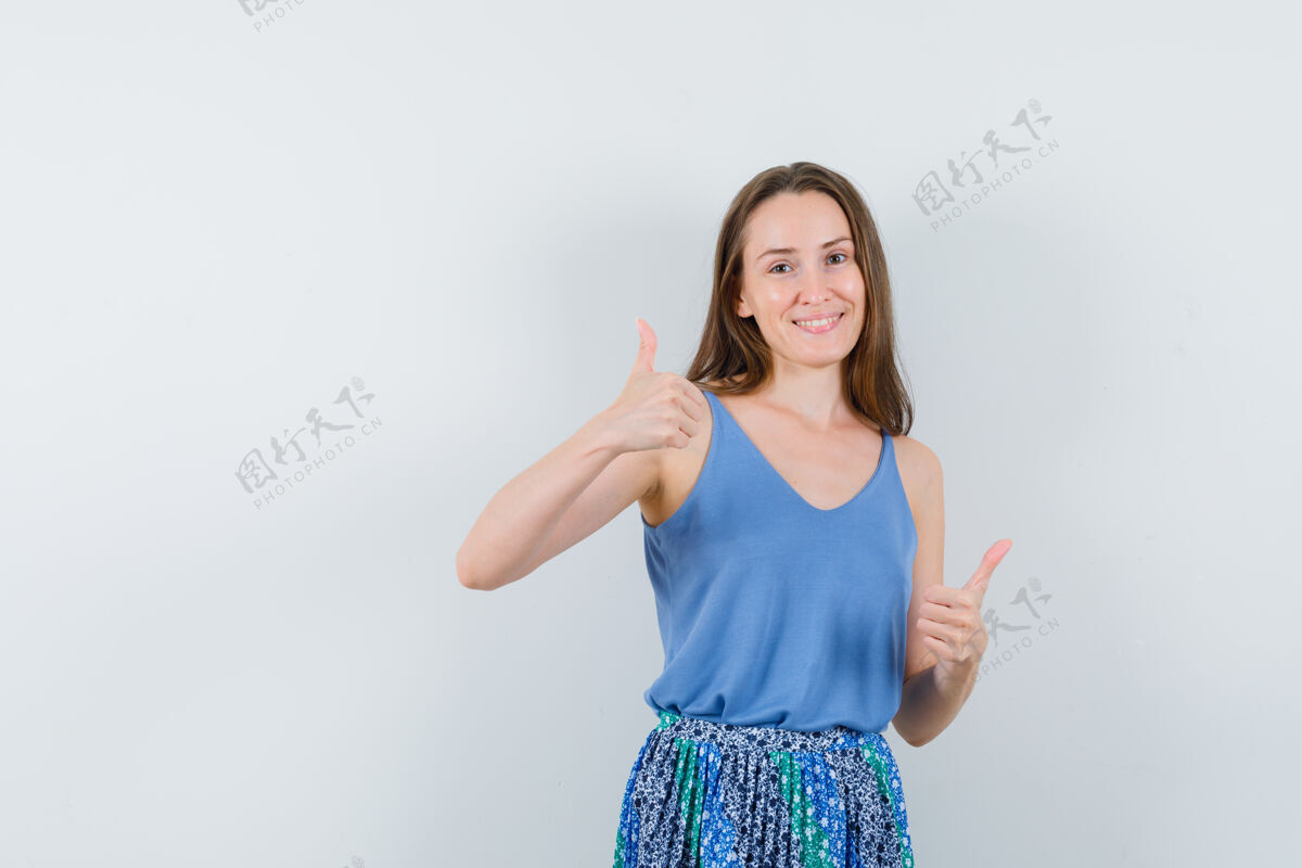 女性年轻女子在单打中竖起大拇指 穿着裙子 看起来很快乐 正面视图人健康裙子