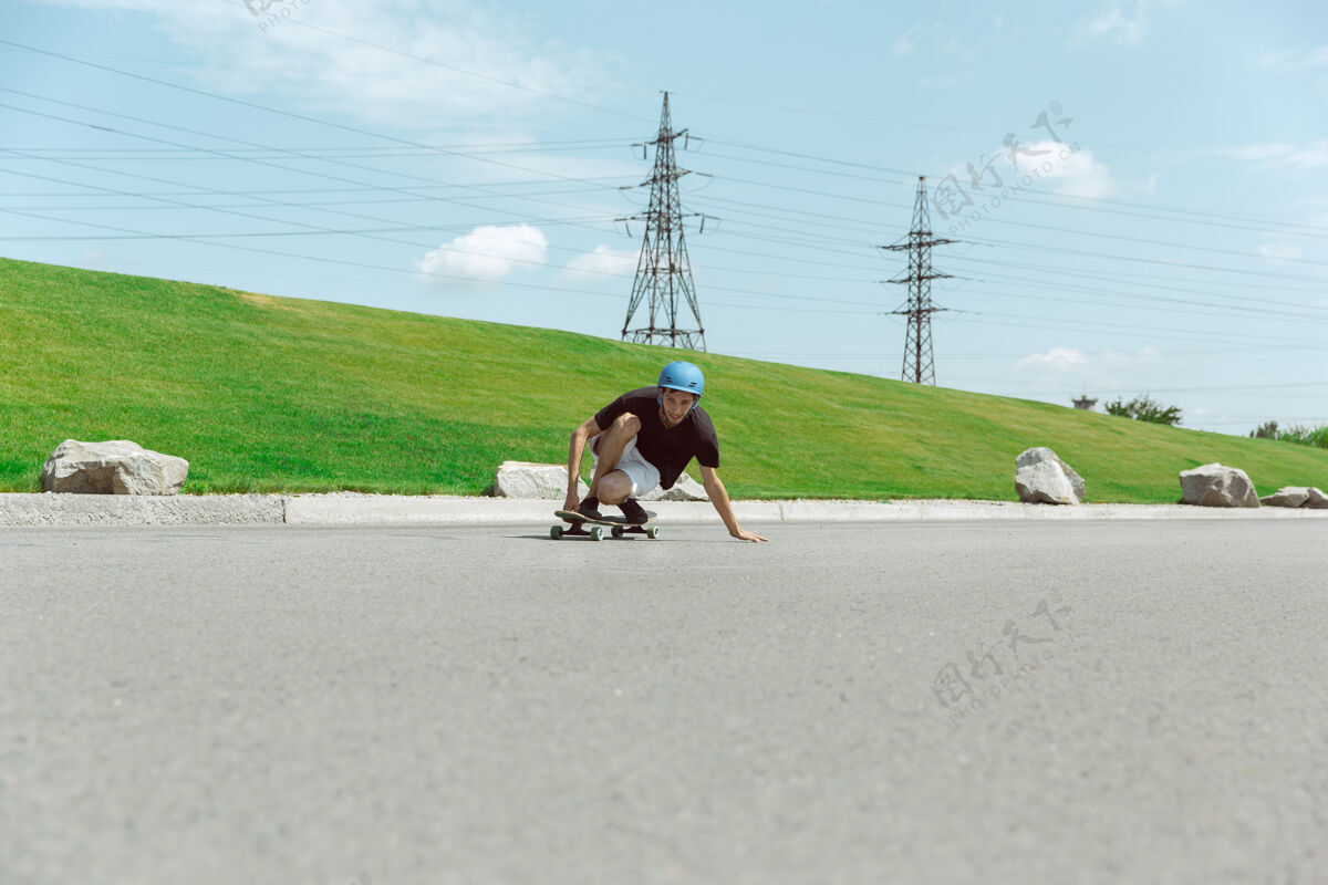 运动员在阳光明媚的日子里 在城市街道上玩滑板的人年轻人在草地附近骑马 玩长板休闲活动 运动 极限 爱好和运动的概念滑板平衡速度