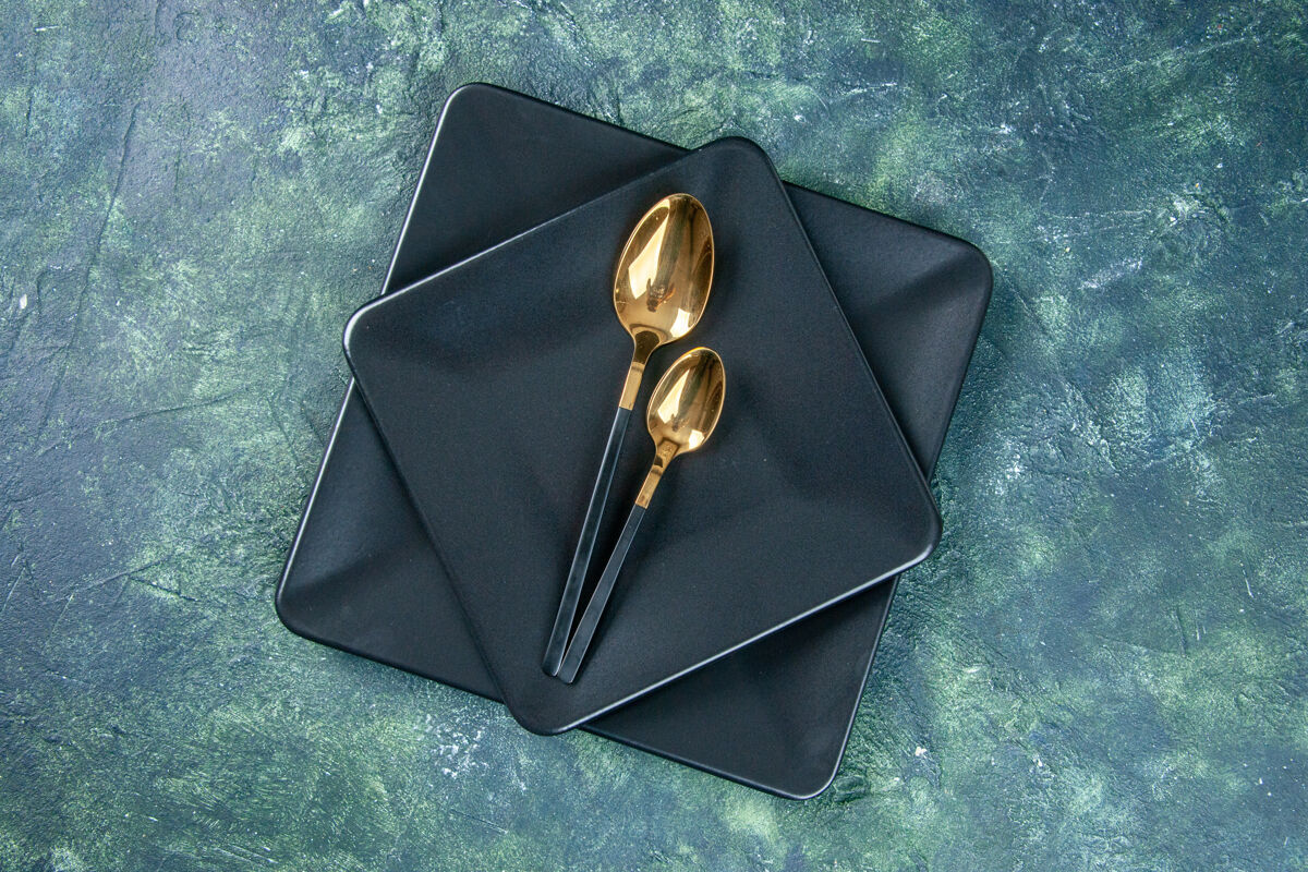 晚餐顶视图黑色盘子和金色的勺子在深色背景上颜色餐具餐厅晚餐咖啡厅食物钱背景