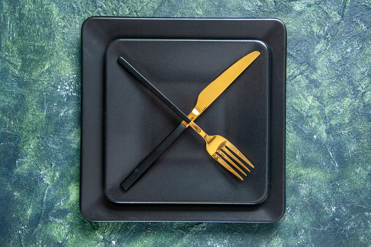 咖啡馆顶视图黑色盘子与金色叉子和刀子交叉在深色表面颜色食品餐具餐厅服务晚餐厨房咖啡厅颜色顶部笔