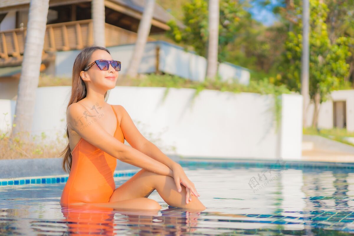 泳装肖像美丽的亚洲年轻女子放松微笑休闲在酒店度假村的室外游泳池周围旅游度假美容阳光海洋
