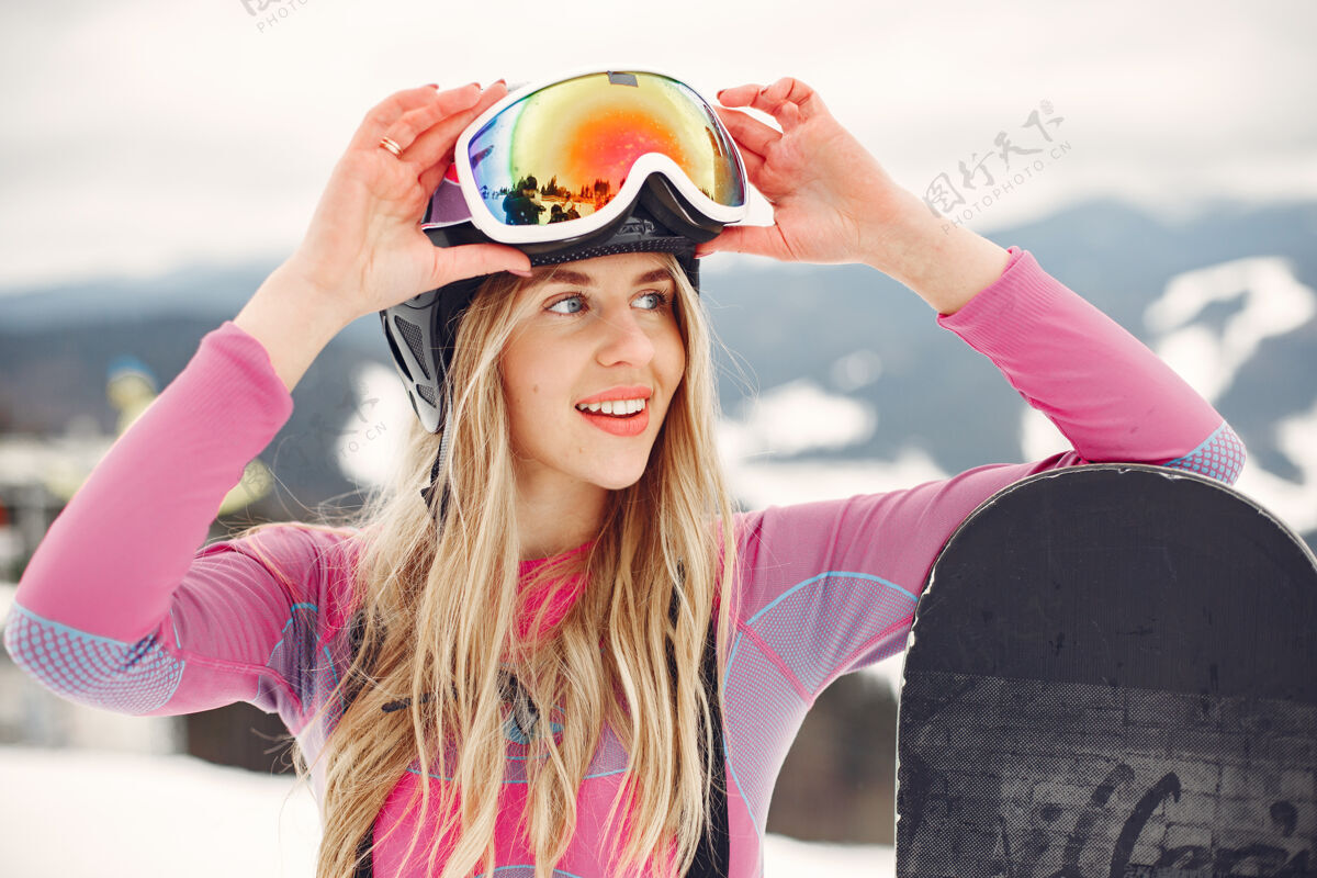 设备穿着滑雪板套装的女人在山上手拿滑雪板的运动员在地平线上关于运动的概念站度假村白色