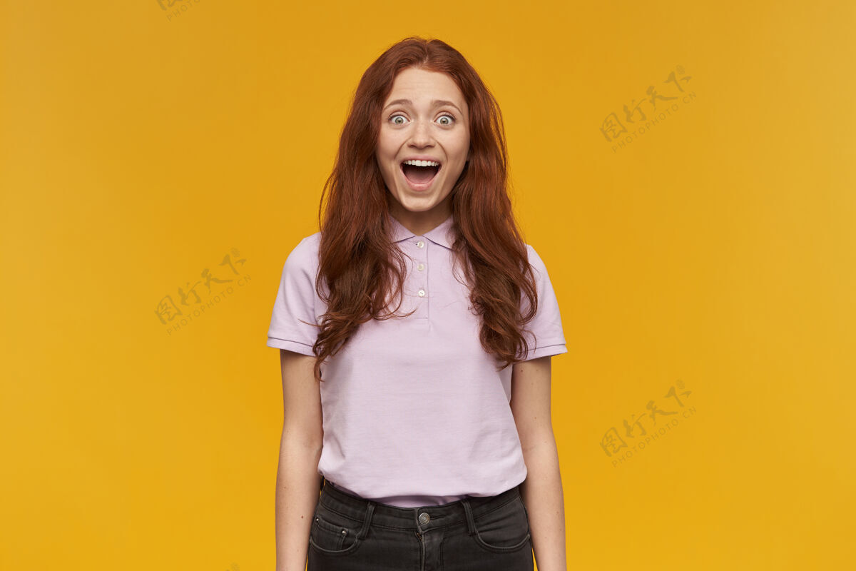 年轻兴奋的 美丽的女士的肖像 长着姜黄色的头发穿着粉红色的t恤人和情感的概念惊讶地看到你被隔离在橙色的墙上人女性肖像