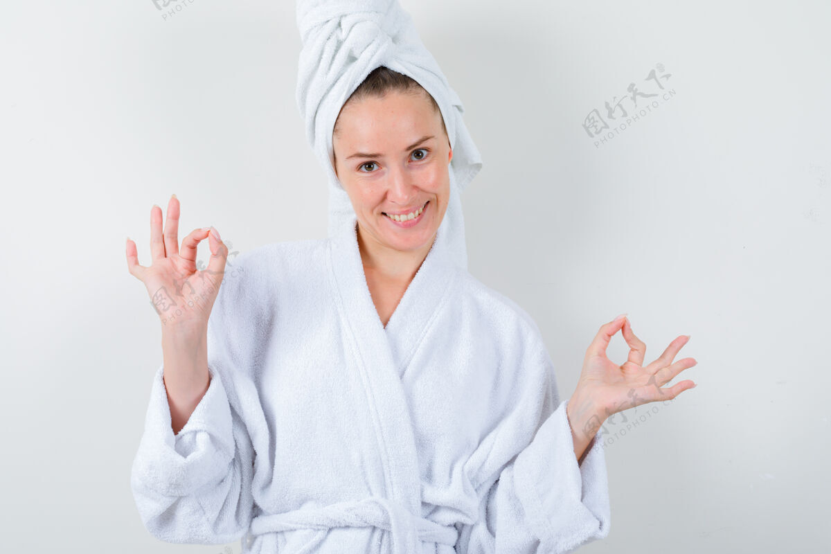 黑发穿着白色浴袍的年轻女士 毛巾显示出良好的姿态 看起来很愉快 正面视图浴袍手势女性