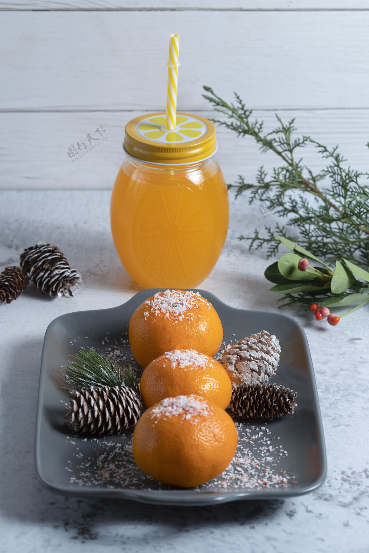 新鲜一盘用粉末和松果装饰的多汁橘子和一罐果汁果皮橘子稻草