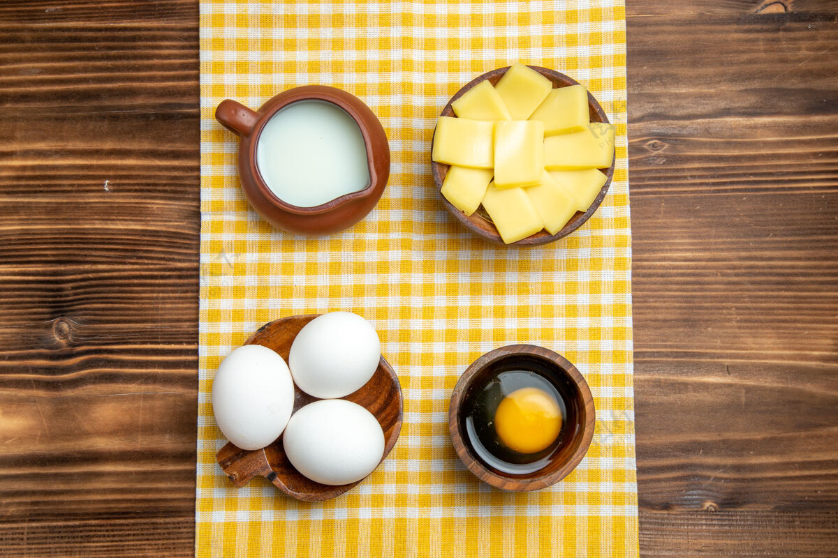有光泽顶视图生鸡蛋与切片奶酪和牛奶在木制表面产品鸡蛋面团餐食品生鸡蛋顶部玻璃杯
