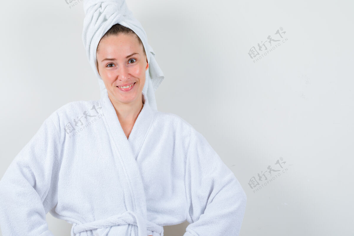前面年轻的女士看着相机 穿着白色浴衣 打着毛巾 看上去很快乐 前视图清洁黑发健康