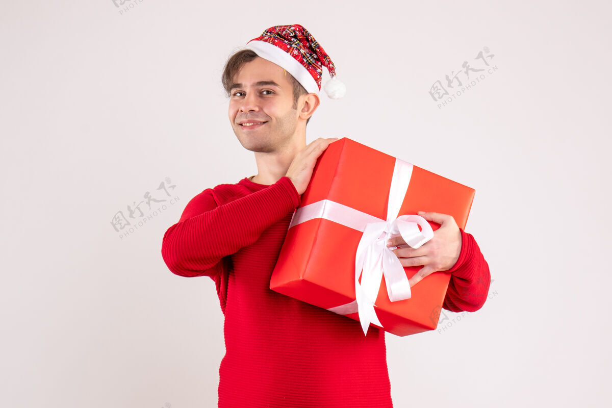 微笑正面图：戴着圣诞帽的年轻人站在白色背景上礼物圣诞节庆祝