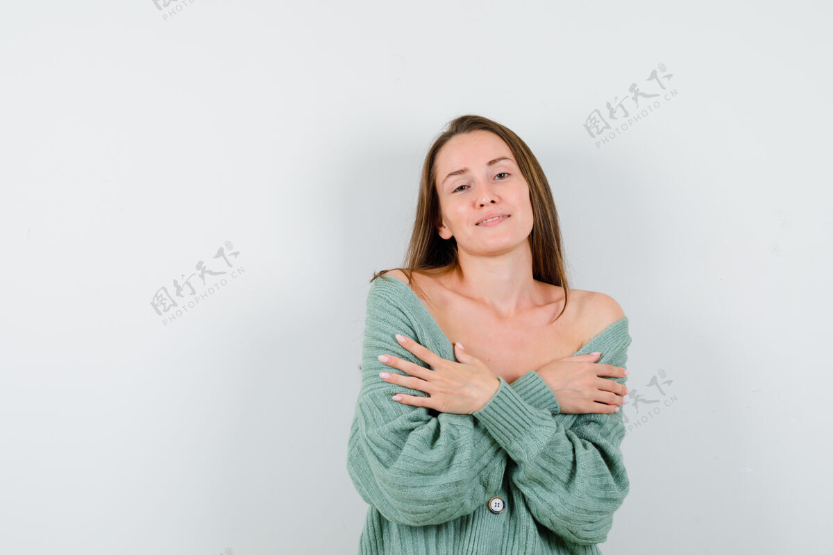 肖像穿着羊毛开衫的年轻女士一边摆姿势 一边拥抱自己 看上去很优雅正面图女人人成人