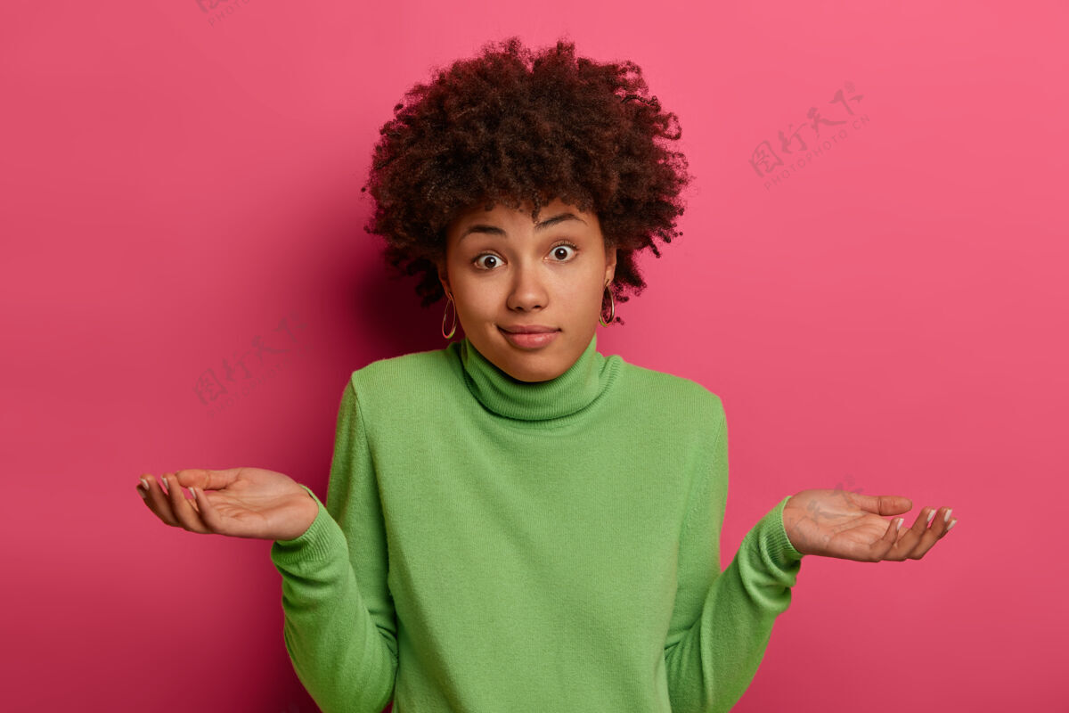 反应冷漠迷茫的黑女人迷迷糊糊地摊开手掌 有疑惑 穿着绿色高领毛衣 有犹豫不决的表情 隔着粉色的空间非洲人怀疑困惑