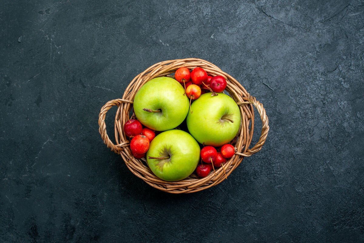 新鲜顶视图篮子上有水果 苹果和甜樱桃 深色表面上有水果 浆果组成的新鲜树樱桃生的可食用的水果