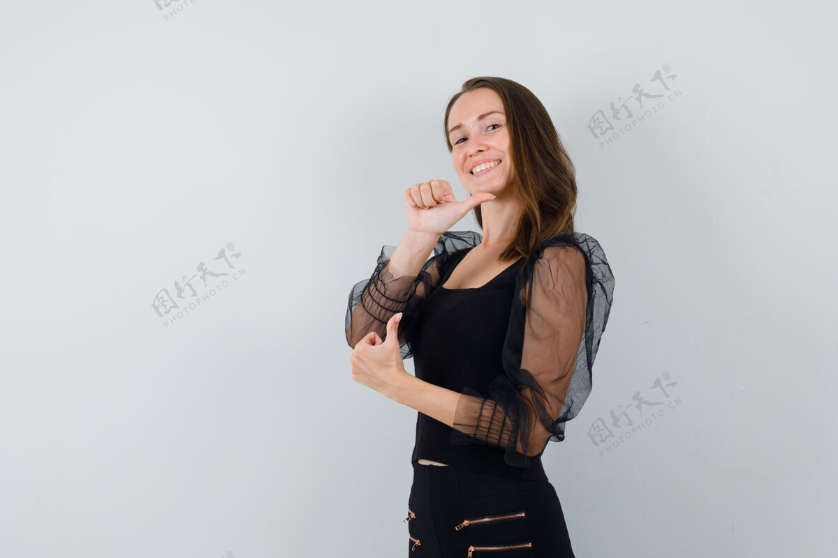 快乐身穿黑色上衣和黑色裤子的年轻女子向上竖起大拇指 看上去很开心正视图双人肖像拇指