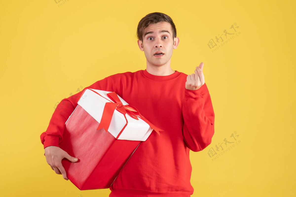 人物正面图黄色背景上穿着红色毛衣赚钱的年轻人标志毛衣男性男人