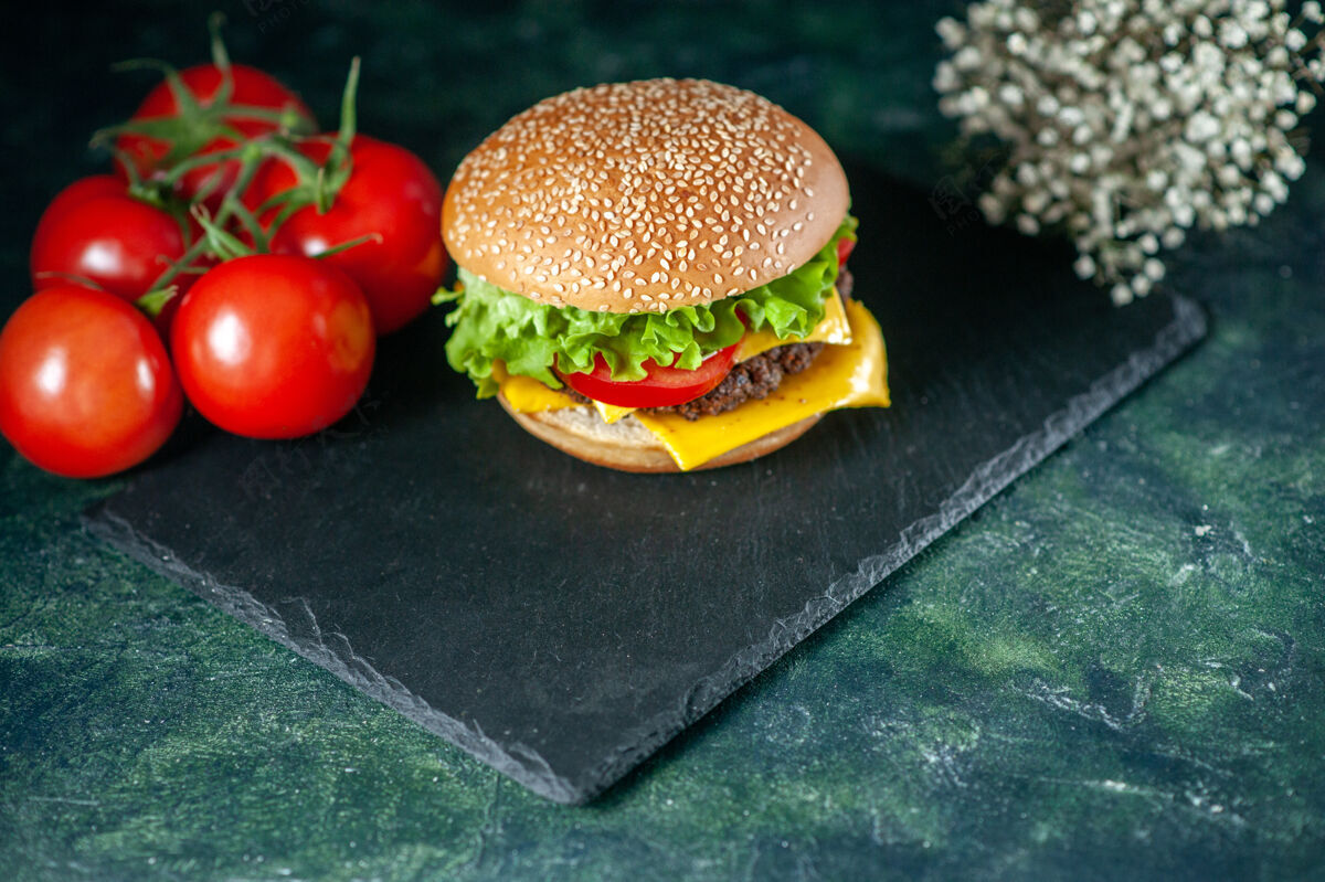 美味前视图美味的肉汉堡包与绿色沙拉奶酪和西红柿在黑暗的背景深色生菜晚餐