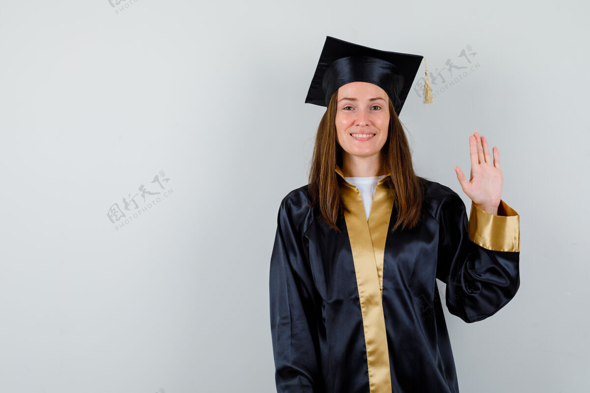 水疗年轻的女毕业生穿着学院服 露出手掌打招呼 看上去很高兴 正面照新鲜魅力健康