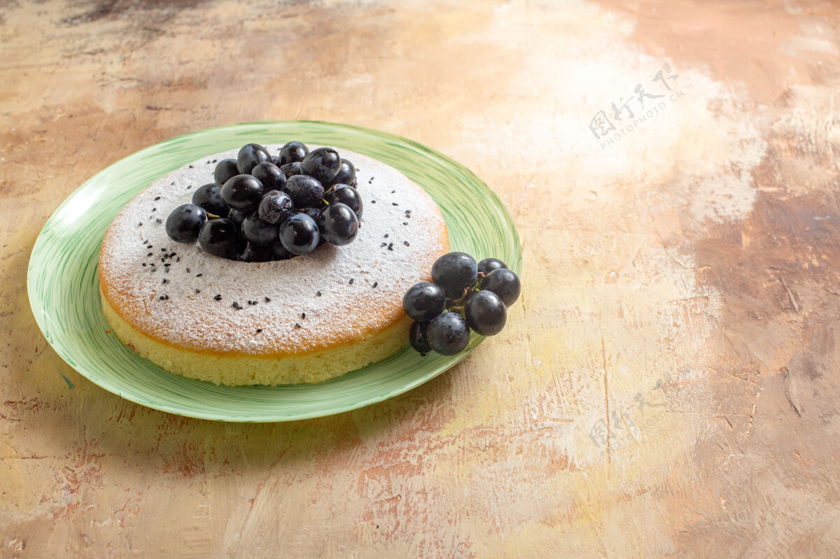 蛋糕蛋糕一个开胃的蛋糕 盘子里放着黑葡萄和糖粉壁板蓝莓美味