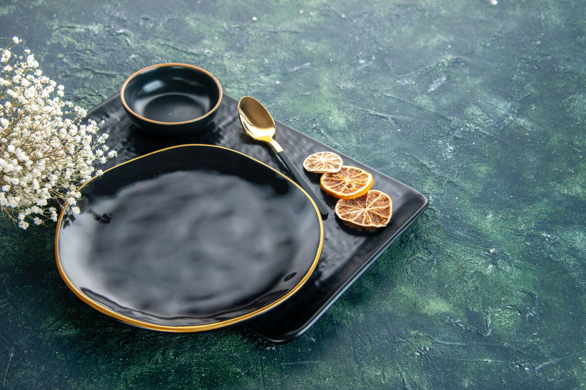 干橘子前视图黑色背景上的黑色板晚餐碗金汤匙