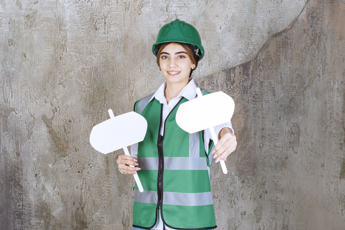 标志身穿绿色制服 头戴安全帽的女工程师 双手拿着两块标牌工人员工位置