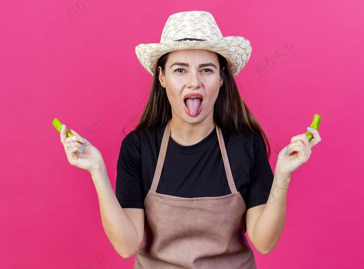 园艺穿着制服的漂亮的园丁女孩戴着园艺帽 手里拿着粉红色背景上孤立的碎胡椒不愉快制服穿