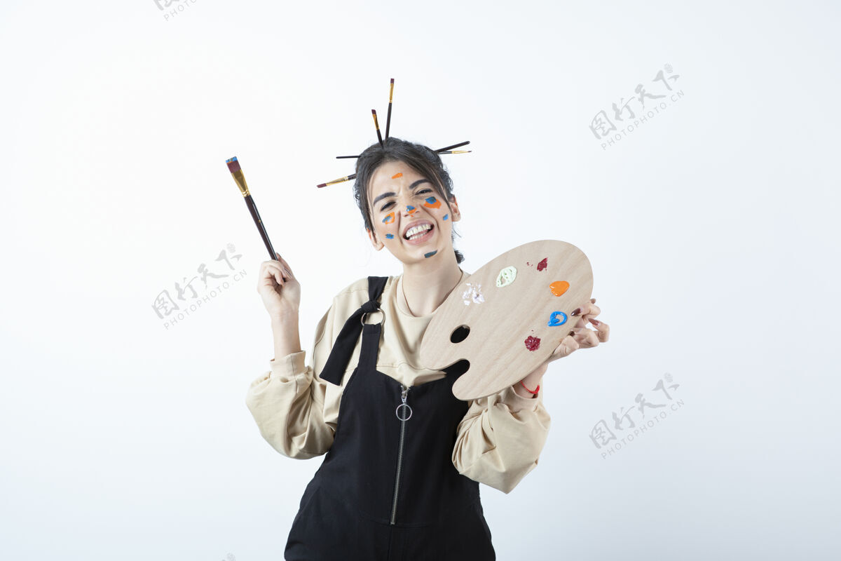 爱好一位年轻女艺术家的肖像画 画着一张脸 拿着木制的调色板女性艺术家画笔