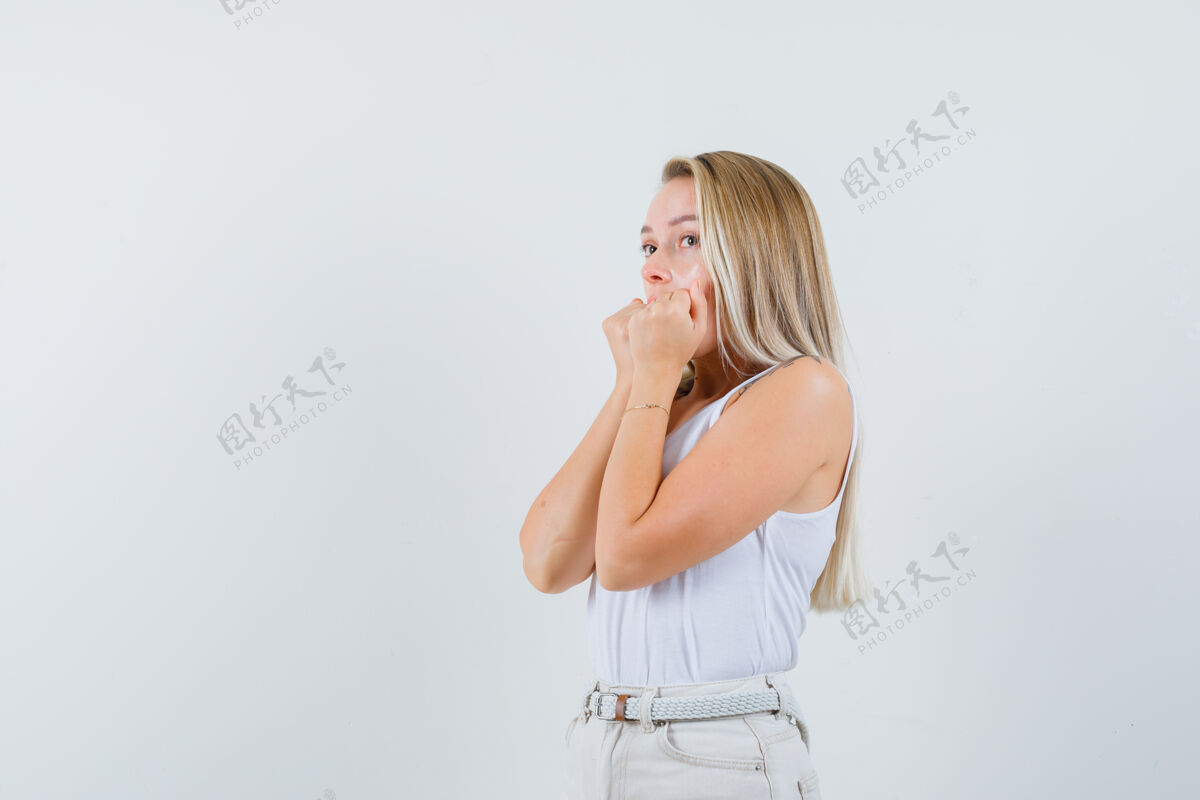 头发这位年轻的女士把拳头放在嘴上 穿着白衬衫向一边看 看上去很不舒服女性漂亮女士