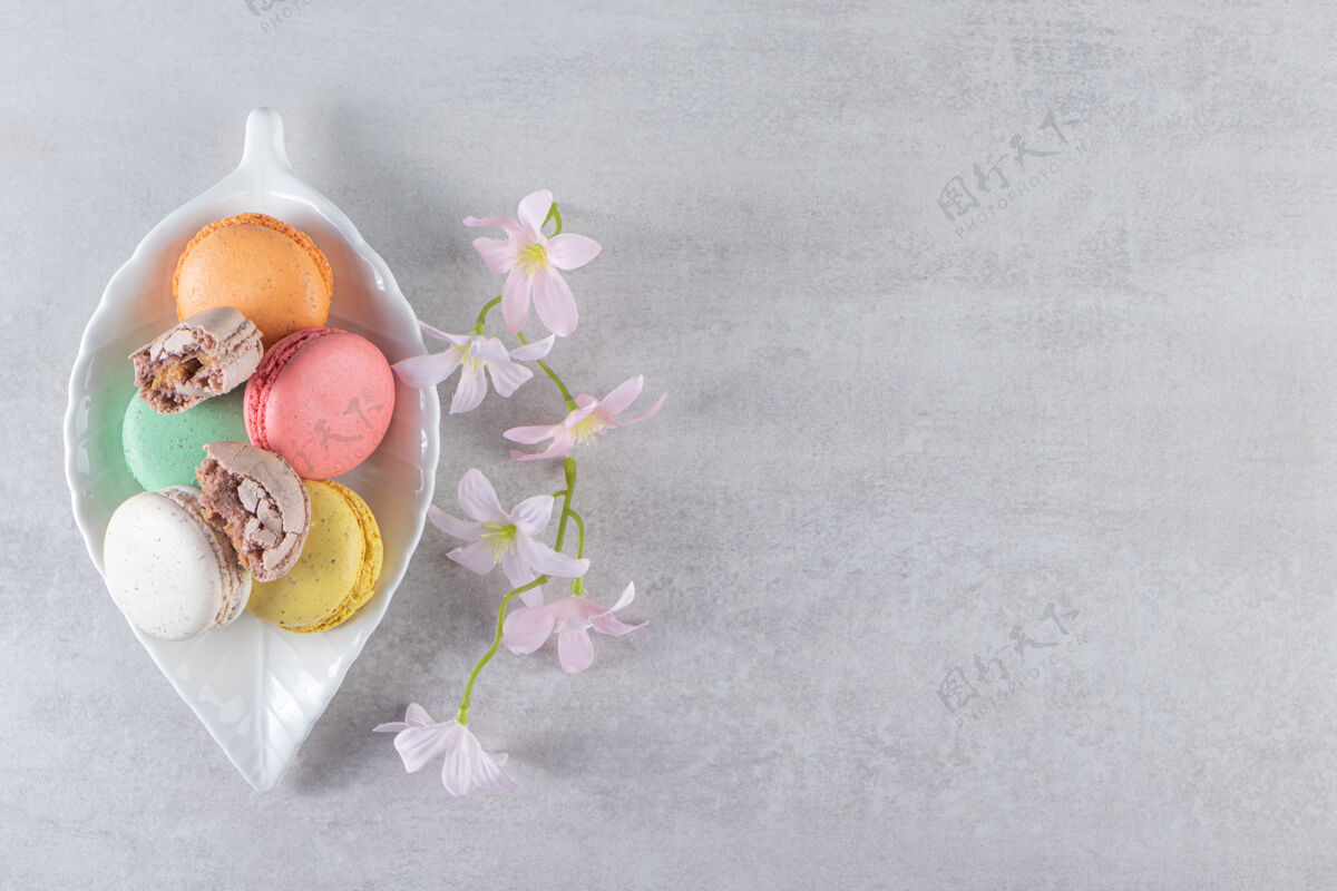 食品石头桌上摆着一盘五颜六色的带花的甜杏仁饼奶油蛋糕糖果