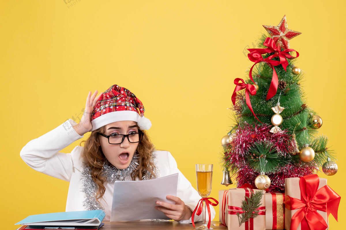 圣诞树前视图女医生在她的桌子后面拿着文件餐桌节日文件