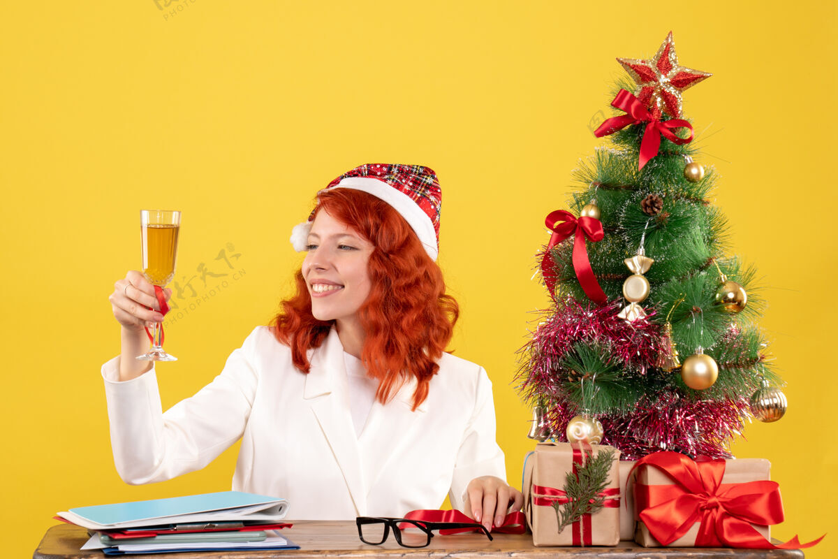 坐正面图女医生坐着用香槟庆祝圣诞节人微笑节日
